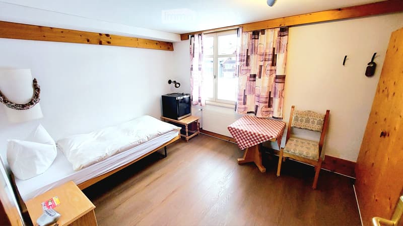 single bed, bedside table, TV, table, chair, window with curtains