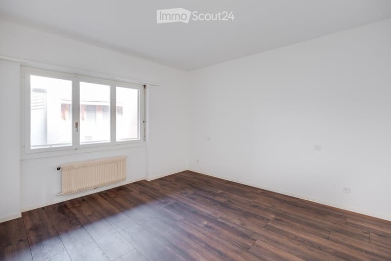 white walls, white radiator, wooden floors, white ceiling, large window