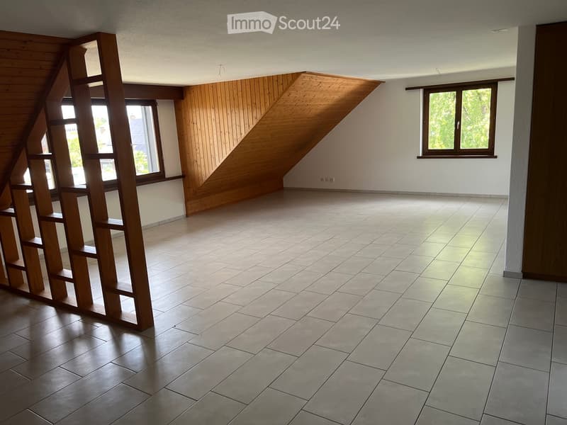 Empty room with wooden slatted shelving unit, tiled floor, and large windows with wooden frames.