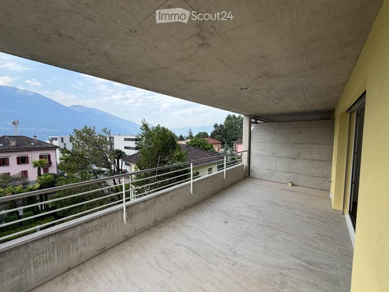 Modern balcony with concrete floor, metal railing, and scenic mountain view.