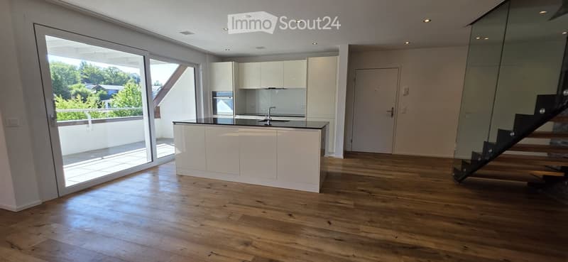 Modern kitchen with white cabinets, wooden flooring, and a large window offering a view of the outdoor area.
