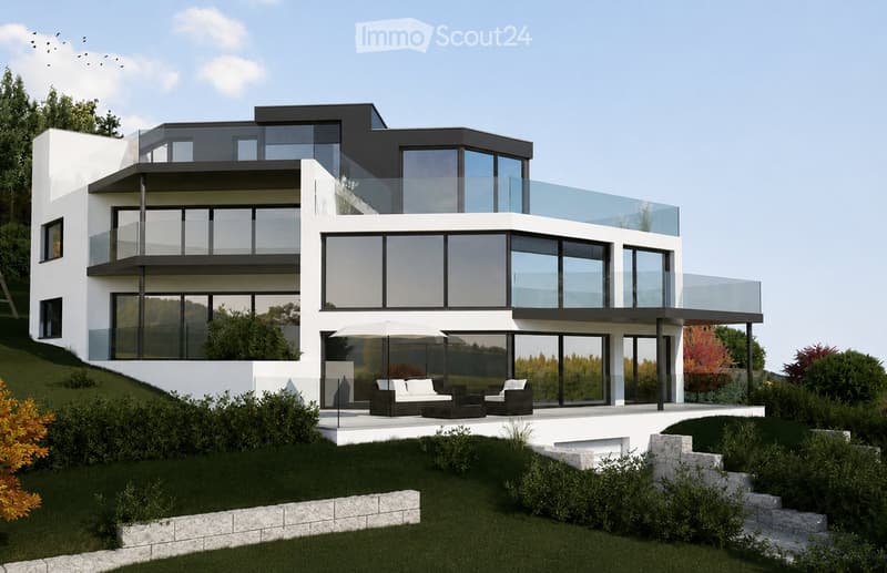 Modern two-story house with white and black exterior, large glass windows, and a raised ground floor. Features include a balcony, outdoor seating area with a sofa and chairs, and a well-maintained garden with shrubs and trees.