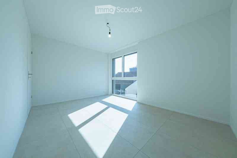 Empty room with white walls, tiled floor, and large window letting in natural light. No furniture or equipment present.