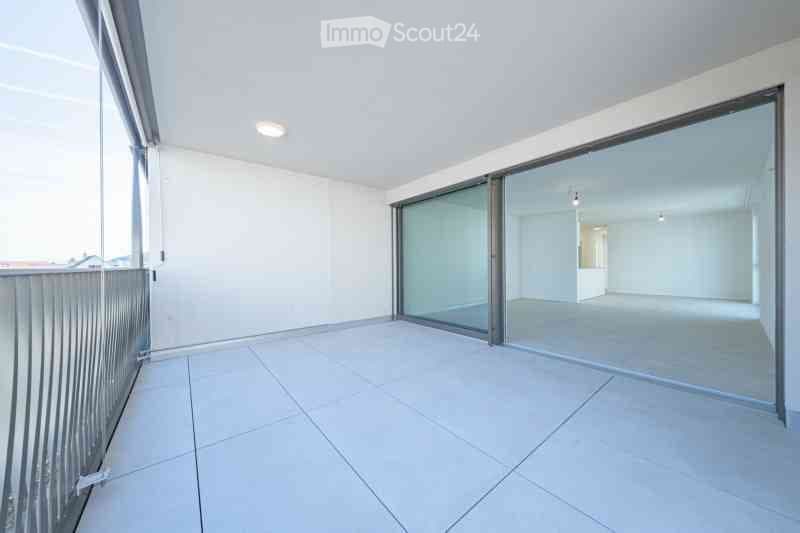 Empty room with white walls, tiled floor, large glass sliding doors, and a metal railing.