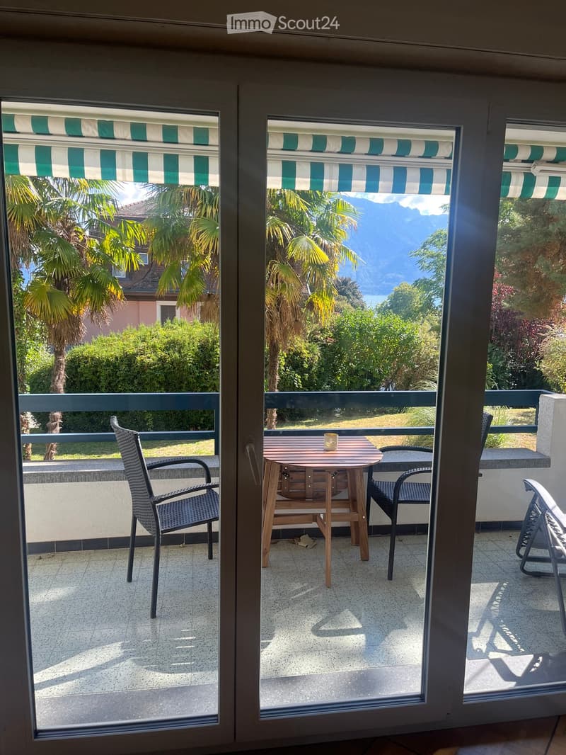 Balcony with a table and chairs, overlooking a scenic view of mountains and palm trees.