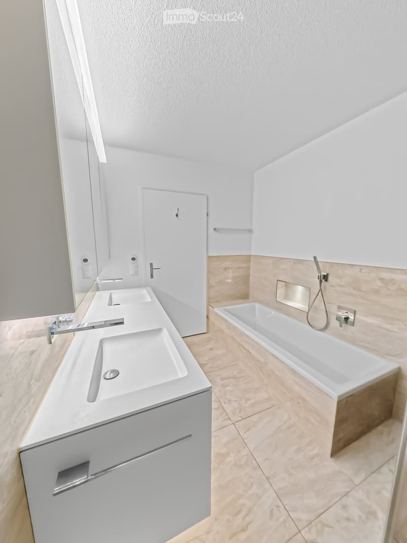 Modern bathroom with a double sink vanity, bathtub, and sleek fixtures.