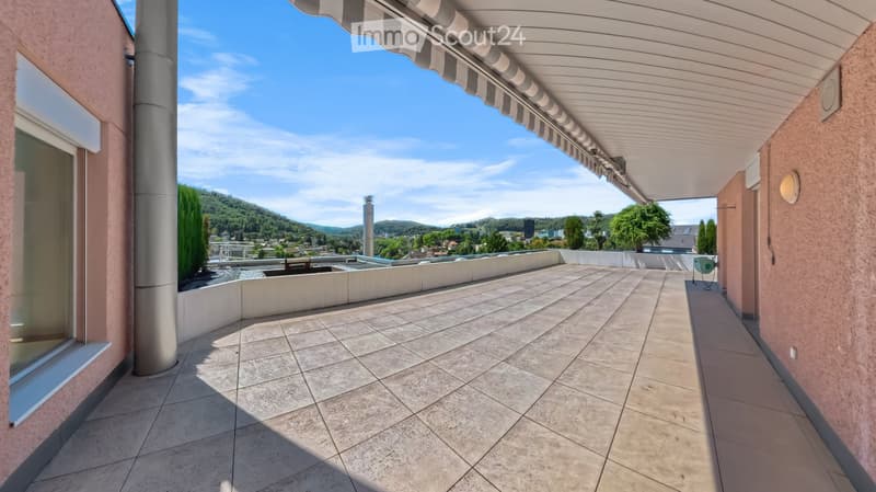 Spacious balcony with tiled flooring, covered awning, and scenic view of the valley and surrounding greenery.