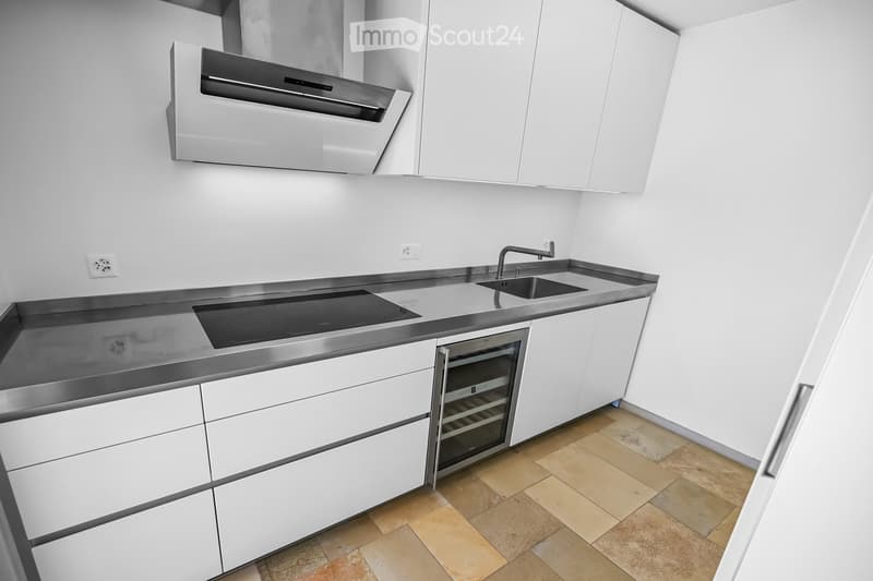 Modern kitchen with white cabinets, stainless steel appliances, induction cooktop, sink, and wine cooler.