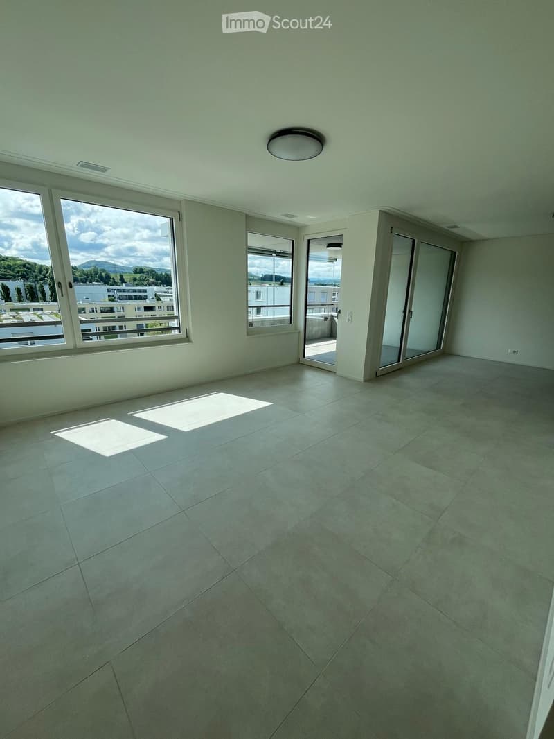 Empty room with tiled floor, large windows, and sliding glass doors leading to a balcony.
