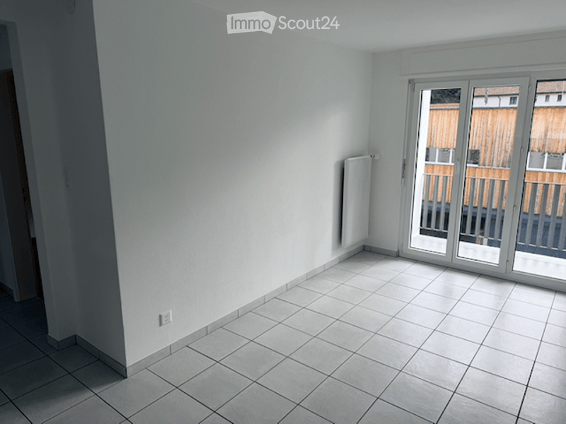 Empty room with white walls, tiled floor, and large sliding glass doors leading to a balcony.