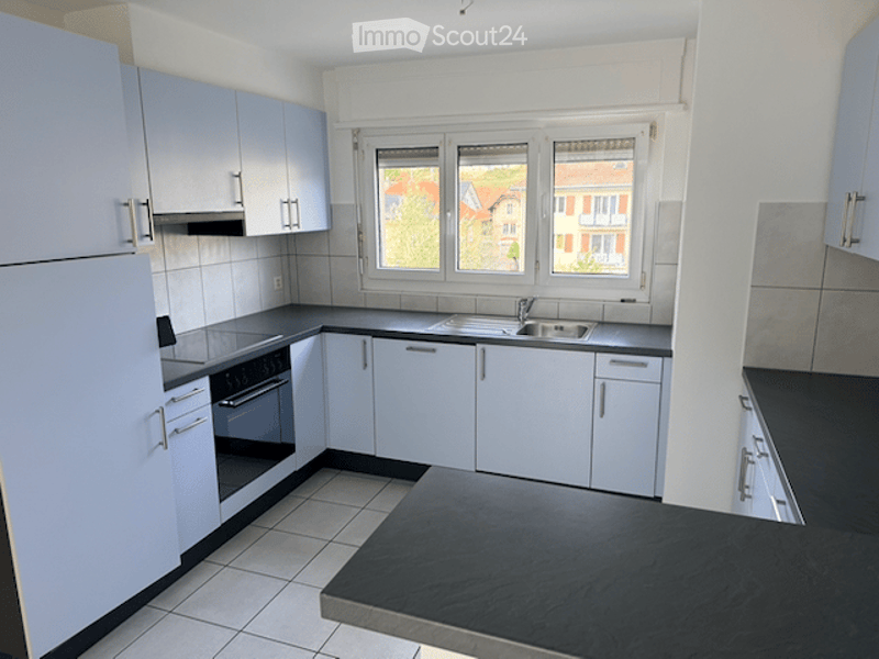 Modern kitchen with white cabinets, black countertops, and stainless steel appliances including a refrigerator, oven, and sink.