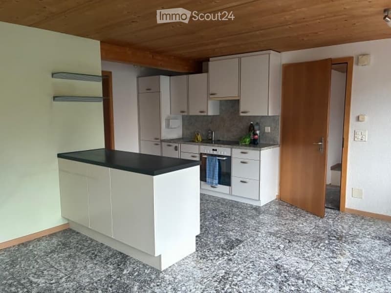 Modern kitchen with white cabinets, black countertop, granite flooring, and stainless steel appliances including a refrigerator, oven, and sink.
