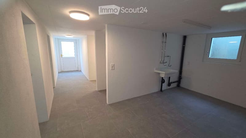 Empty hallway with tiled floor, white walls, and a small sink area visible at the end.