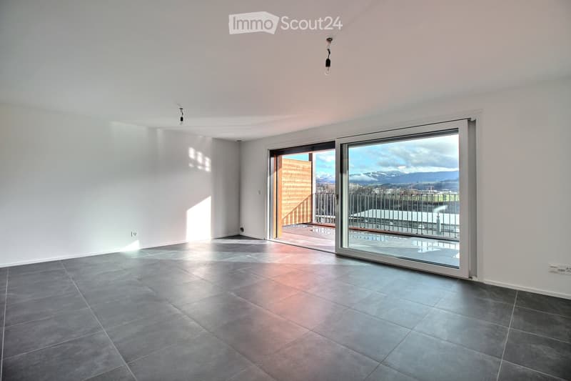 Empty room with grey tiled floor, white walls, and large sliding glass doors leading to a balcony with a scenic mountain view.