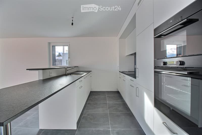 Modern kitchen with white cabinets, black countertops, and stainless steel appliances including a sink, faucet, and oven.
