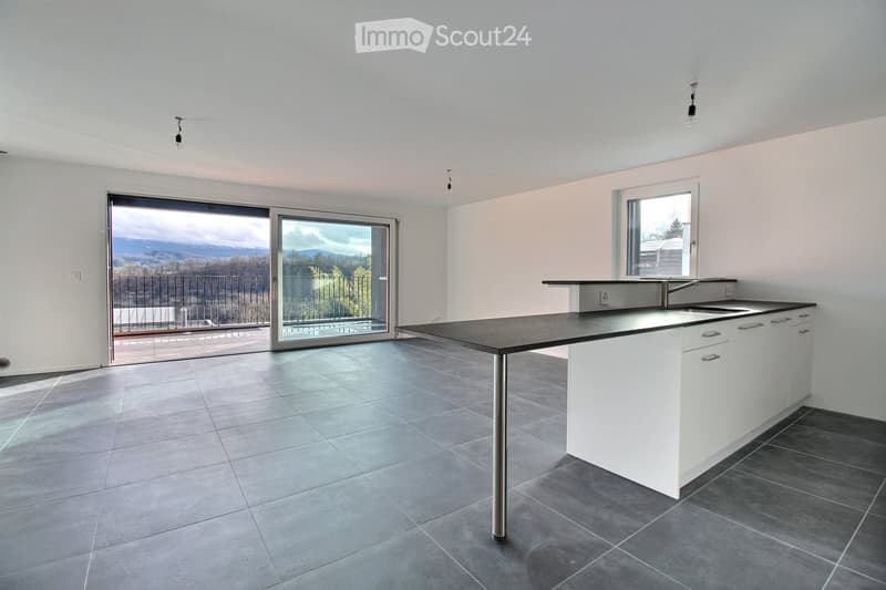 Modern kitchen with white cabinets, a central island, and a sink, featuring large windows and a sliding glass door leading to a balcony with a scenic view.