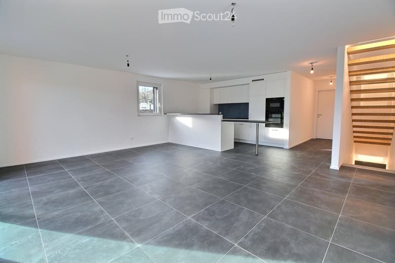 Empty kitchen with white cabinets, dark countertops, and a tiled floor. No furniture or appliances are present.