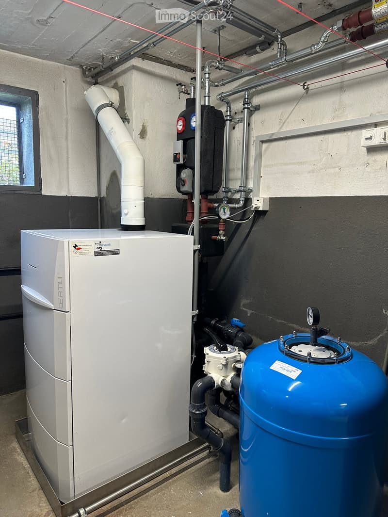 Utility room with water tank, water pump, valves, and pipes.