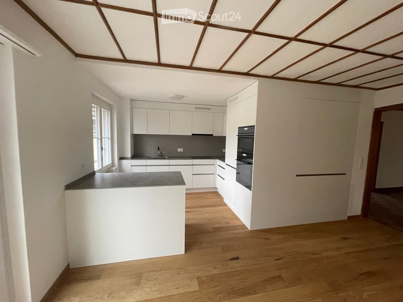 modern kitchen with white cabinets, wooden floor, integrated appliances, bright lighting