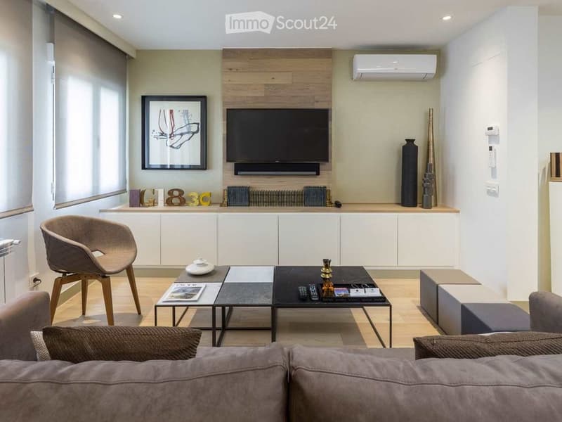 Modern living room with a grey sofa, wooden coffee table, TV mounted on a wooden wall, and decorative vases.