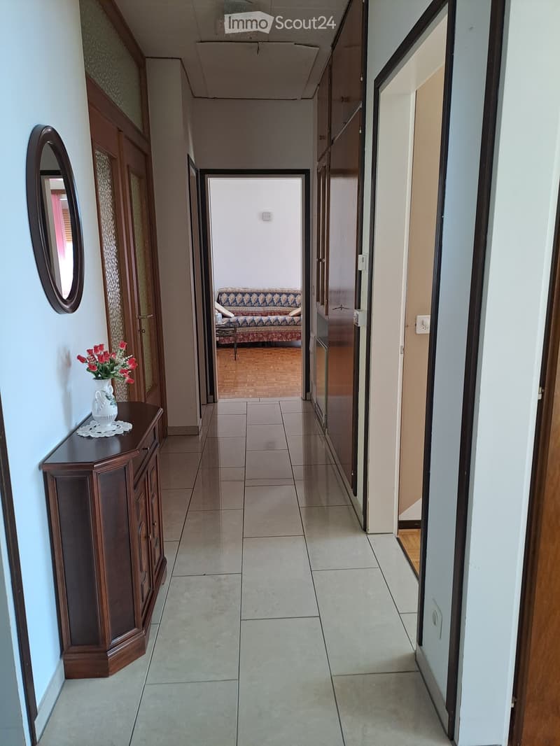 tiled floor, wooden cabinet with flowers, mirror, open doors, living room with couch