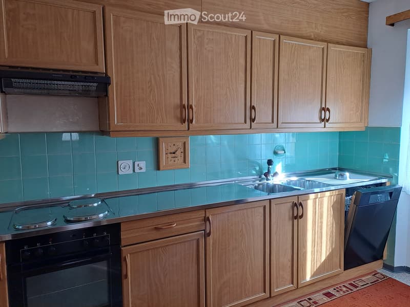 wooden cabinets, blue tiles, stainless steel countertop, gas stove, oven, sink, dishwasher, clock