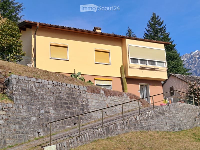 2 story house, yellow exterior, brown roof, stone wall, staircase, balcony, windows with shutters