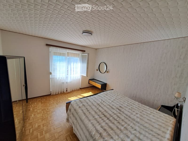 Bedroom with bed, mirror, nightstand, cabinet, and window with curtains