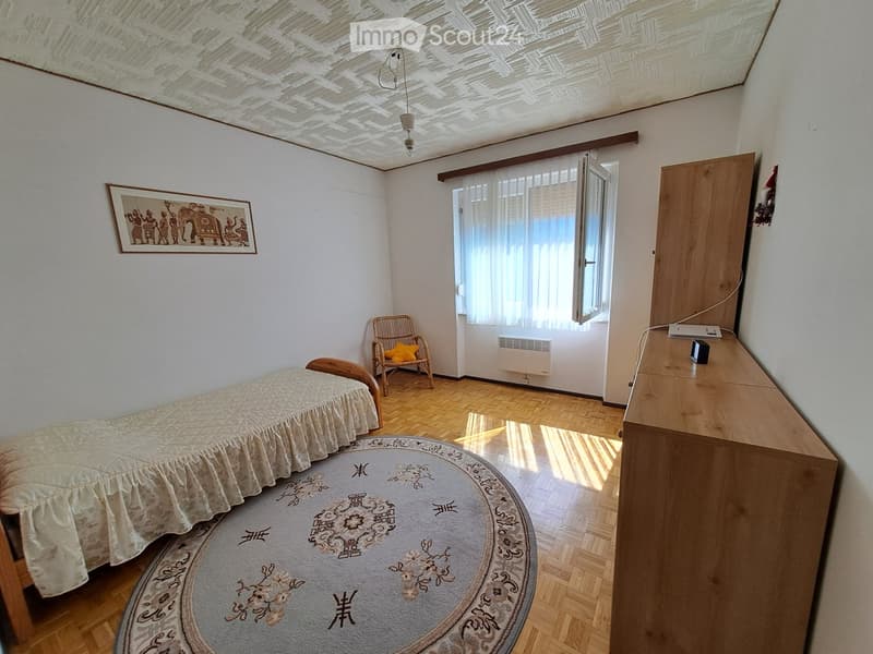 single bed, wooden chair, round rug, wooden cabinet, picture frame, window with curtains