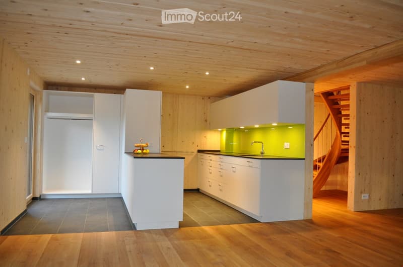 Modern kitchen with white cabinets, wooden ceiling, and a green backsplash. Features a sink, countertop, and a small fruit arrangement on the counter.