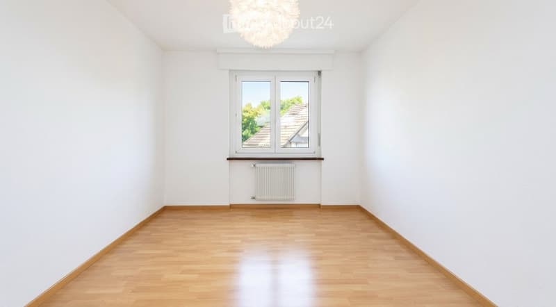 Empty room with white walls, wooden floor, large window, radiator, and a decorative ceiling light fixture.