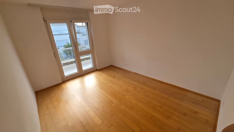 Empty room with wooden flooring and large sliding glass doors leading to a balcony.