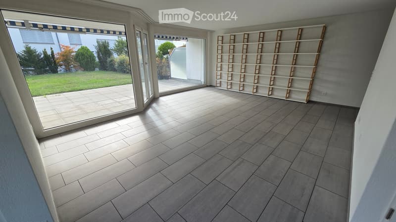 Empty room with tiled floor, large glass doors leading to a patio, and a built-in shelving unit against the wall.