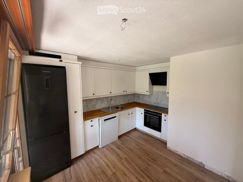 Modern kitchen with white cabinets, wooden countertops, and stainless steel appliances including a refrigerator, dishwasher, oven, and microwave. The floor is wooden, and the backsplash features a marble design.