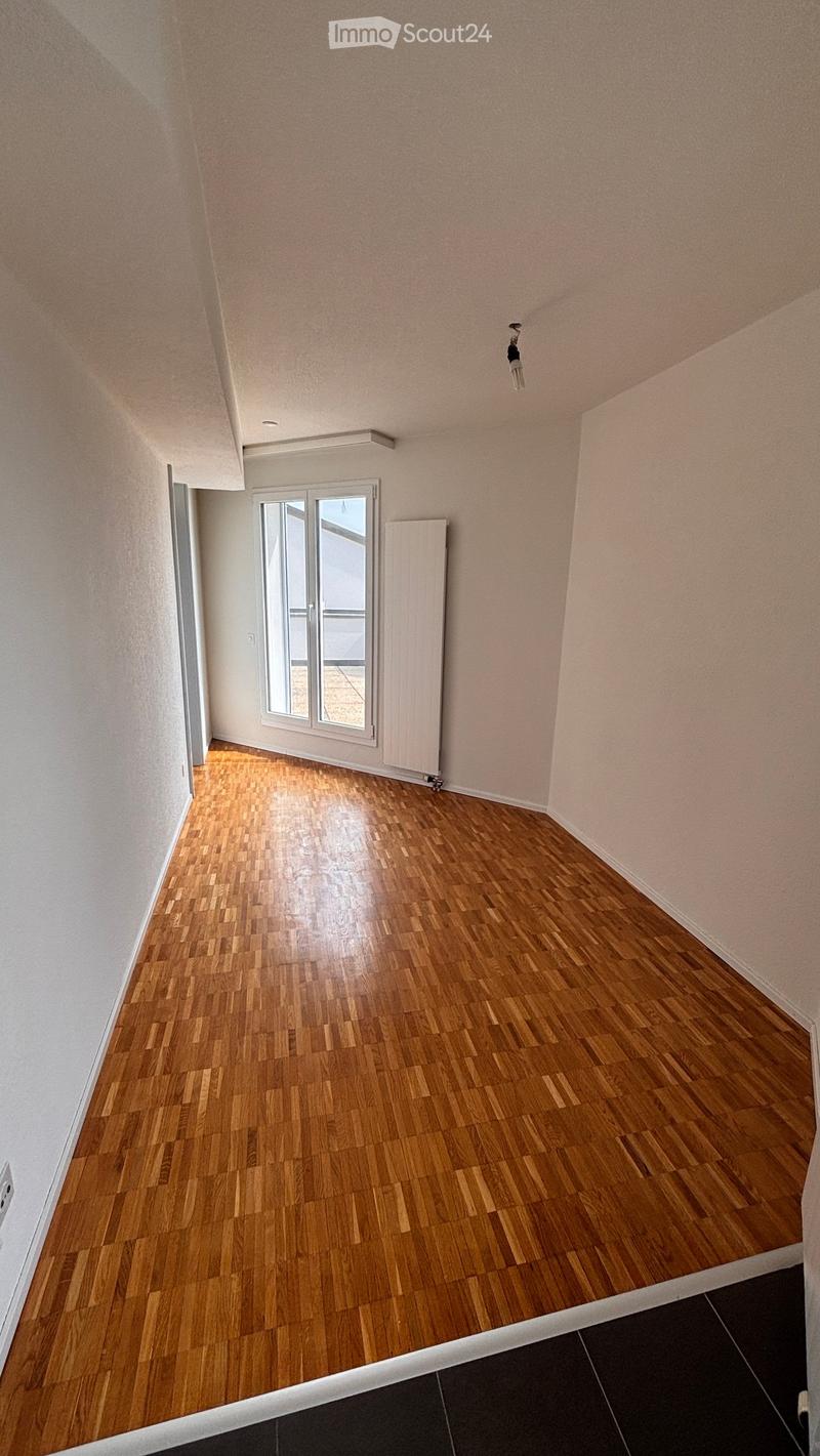 Empty room with wooden flooring, light-colored walls, and a large window with glass panels. No furniture or equipment is present.