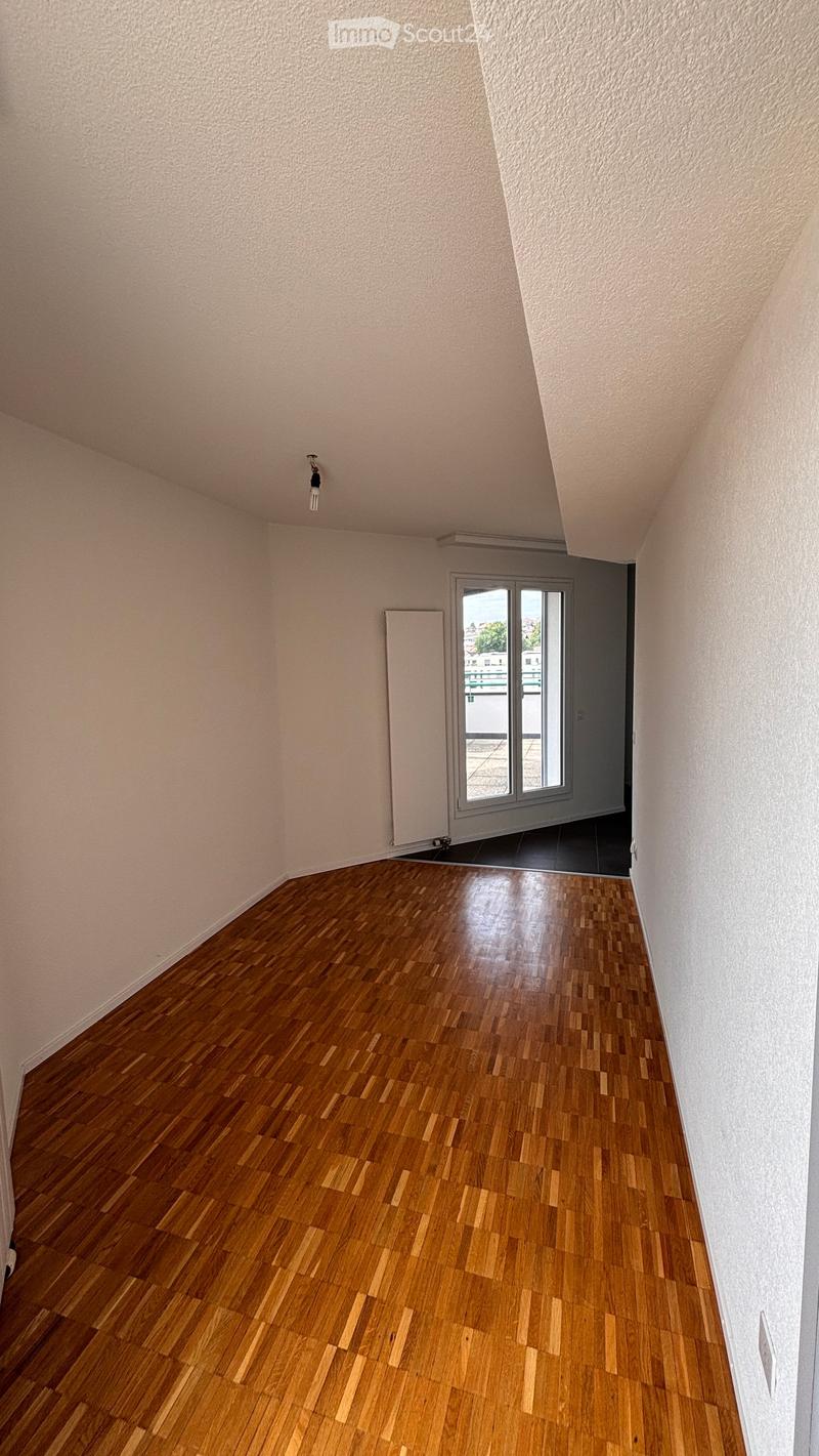 Empty room with wooden flooring, white walls, and a sliding glass door leading to a balcony.