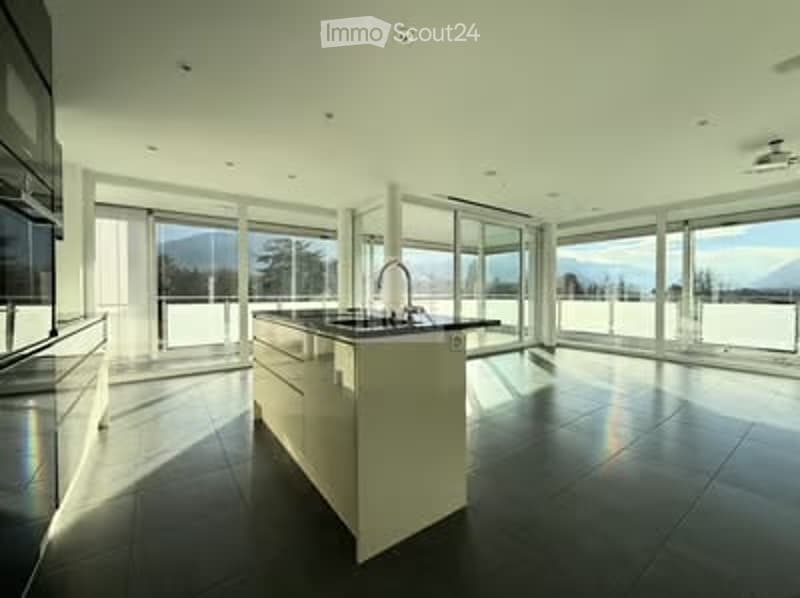 Modern kitchen with large windows offering a scenic view, featuring a central island, sleek cabinets, and a contemporary faucet.