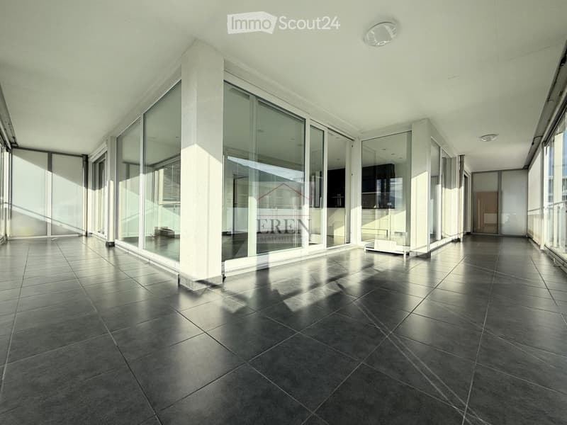 Empty room with large glass windows and polished tile flooring, featuring white walls and modern lighting fixtures.