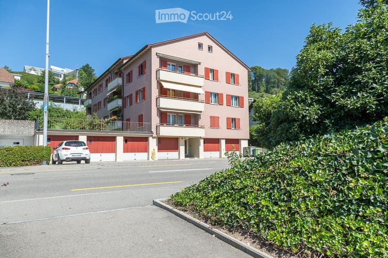 apartment building with 4 floors, 3 garages in front of the building, car parked in front of the garages