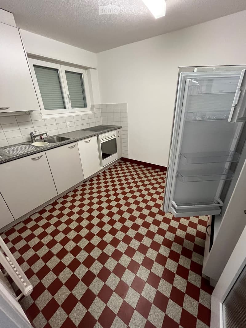Modern kitchen with white cabinets, granite countertop, stainless steel sink, and a red and white checkered floor.