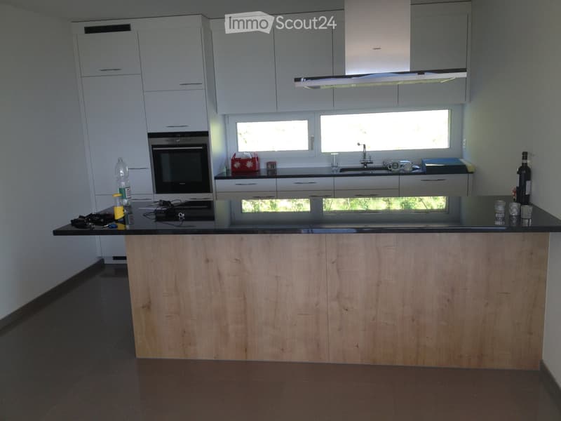 Modern kitchen with white cabinets, a wooden island, and stainless steel appliances. Features an oven, sink, and various small items on the counter.