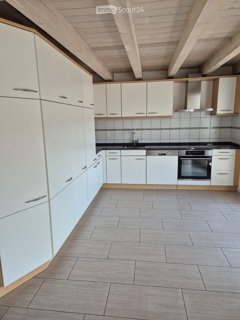 Modern kitchen with white cabinets, stainless steel appliances, and grey tiled backsplash.