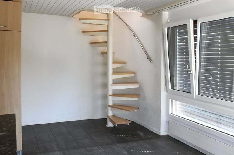 Stylish spiral staircase, modern wooden flooring, white walls, white doors, window with blinds, white radiator, open space