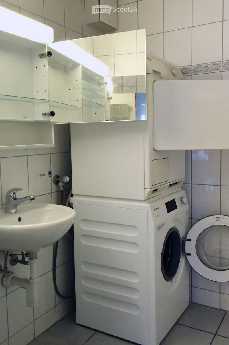modern tiled walls, white tiled floor, white washing machine, white dryer, white sink, white cabinetry