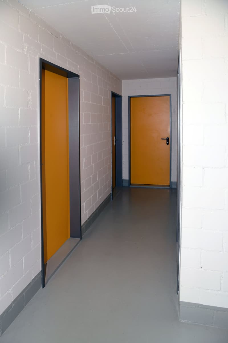 Garage hallway, two doors on either side, grey flooring, white brick walls