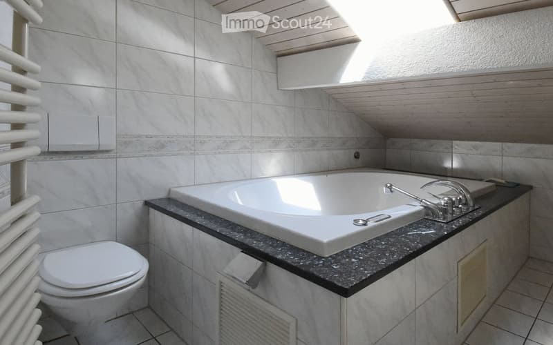 Modern bathroom, white walls, ceiling light, bathtub, shower fixtures, toilet