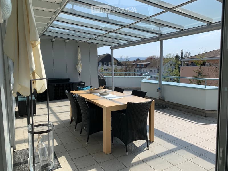 Balcony with a glass roof, tiled floor, and a dining setup including a table and chairs.