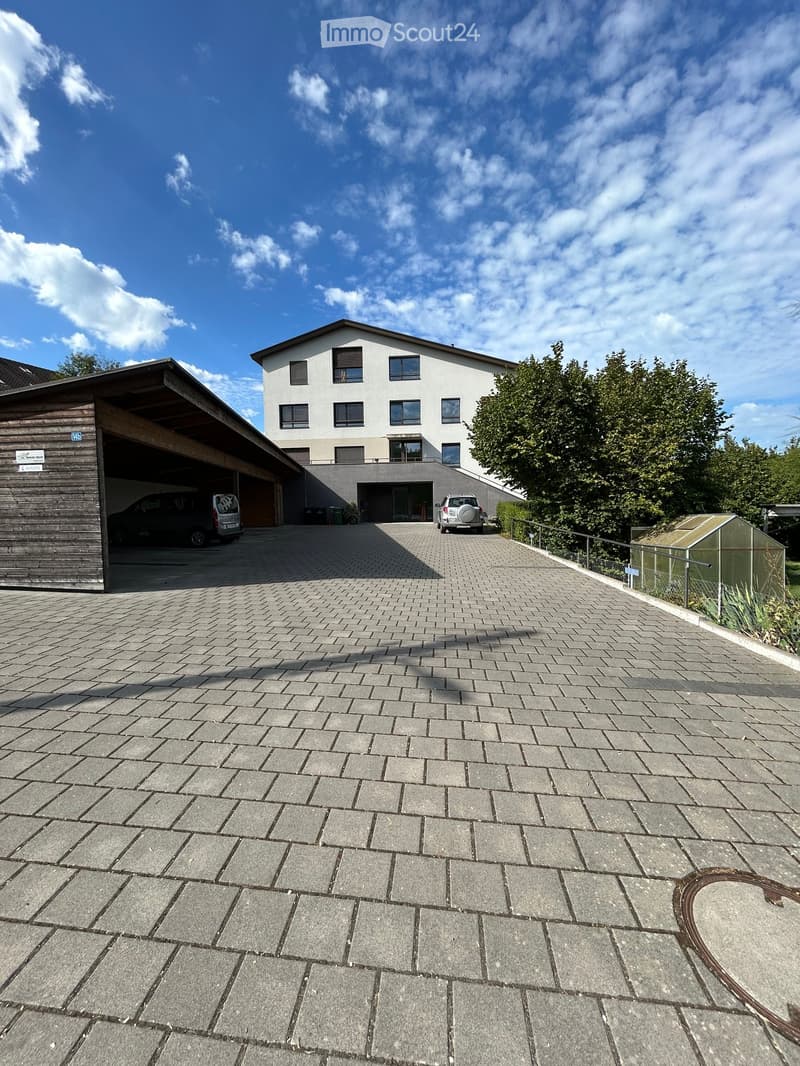 Two-story house with a modern design, featuring a garage and a paved driveway.