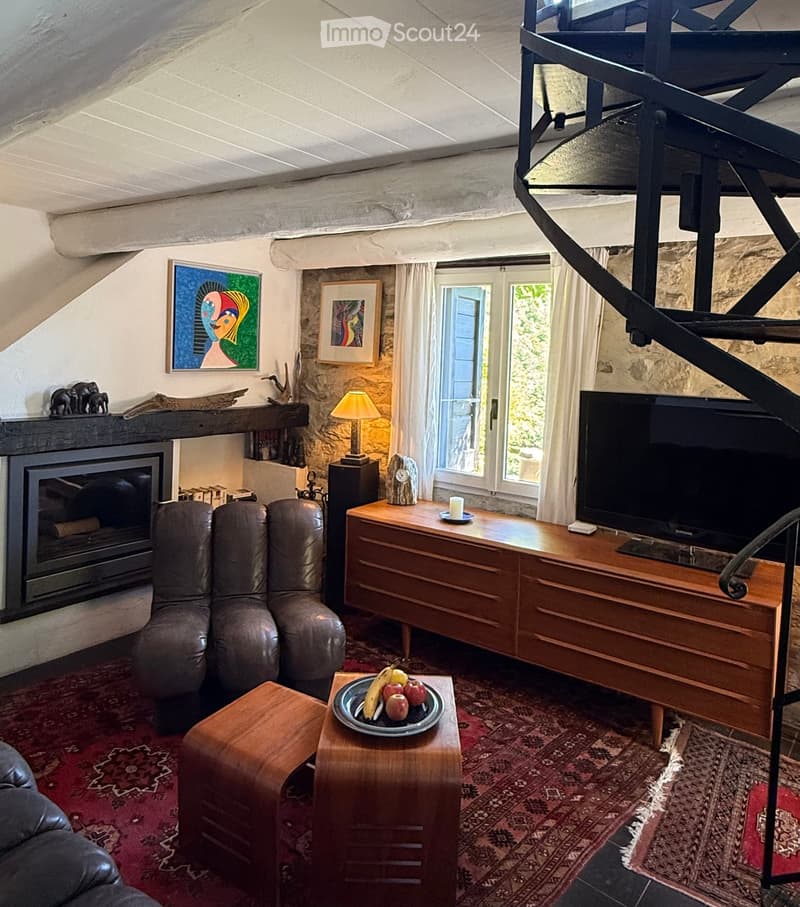 Living room with a fireplace, leather sofa, coffee table, television, and decorative items.