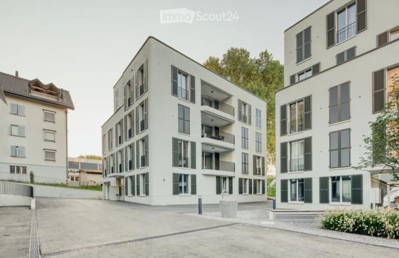 Modern multi-story residential building with white facade, large windows, and balconies.